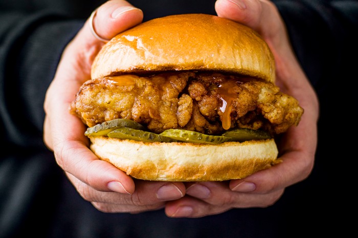 Fried chicken sandwich being held in hands