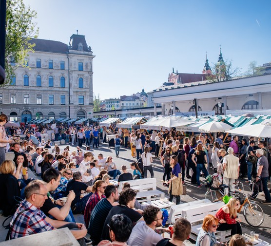 olive travels: where to visit in July People sat on the pavement by street food stalls at the Open Kitchen Market in Ljubljana