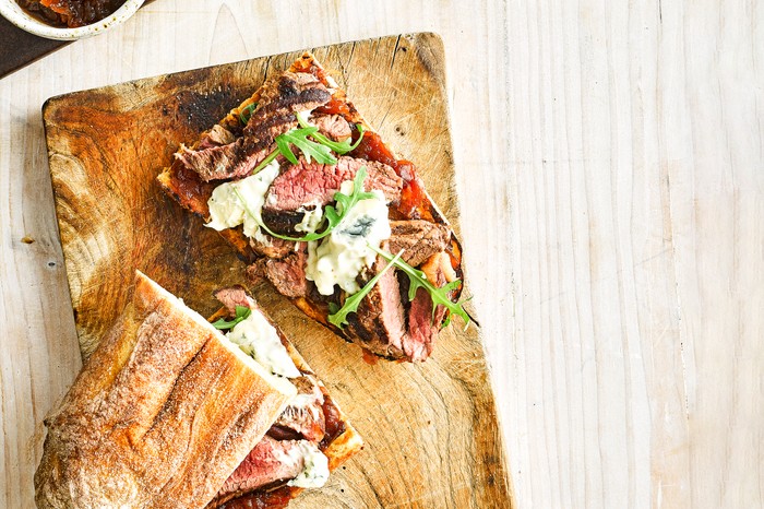 A steak ciabatta sandwich on a wooden board