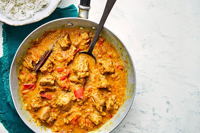 Pan of lamb bhuna next to a bowl of rice