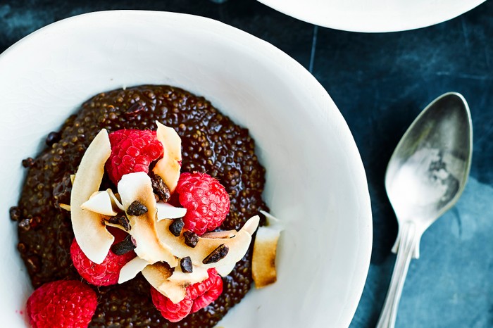 Bowl of chocolate quinoa porridge topped with raspberries and coconut shavings