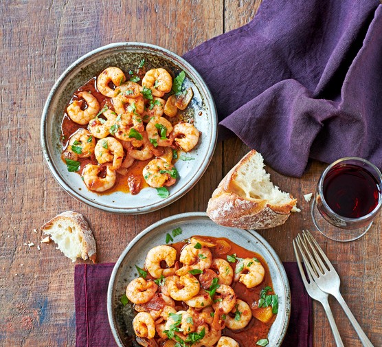 Two grey bowls filled with prawns in a red chilli garlic sauce and topped with chopped parsley