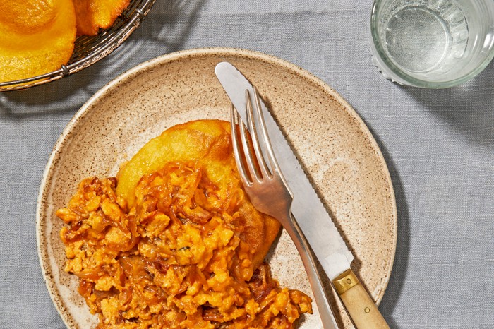 A brown plate topped with fried tortillas and orange scrambled eggs