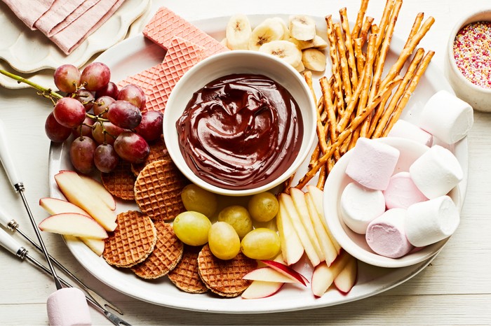 Melted chocolate in the middle of a sharing plate with marshmallows, biscuits, fruit etc