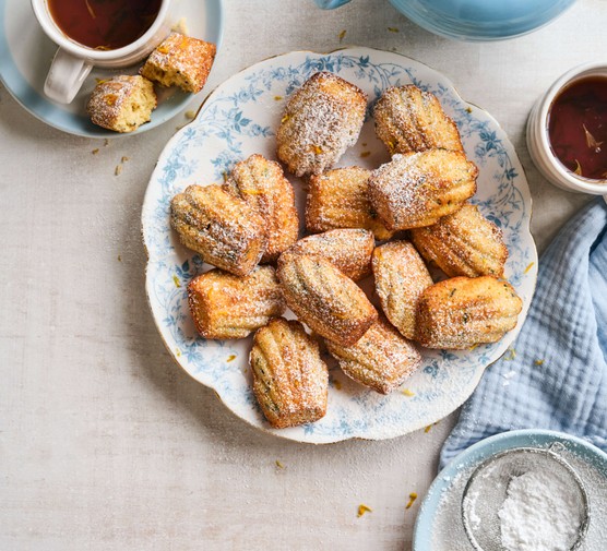 A plate of earl grey yoghurt madeleines next to a cup of coffee