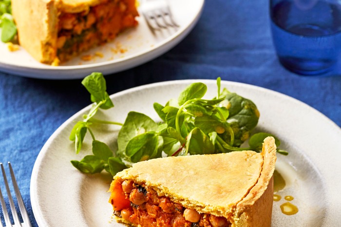 A blue tablecloth topped with two plates, each one topped with a slice of squash pie with green leaf salad