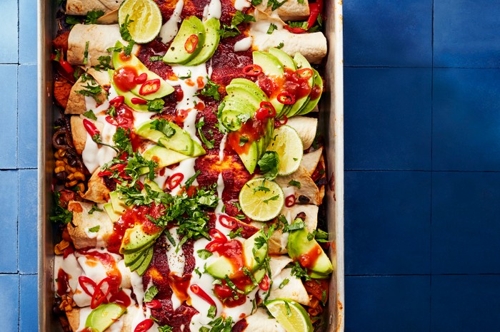 Baking Tray Filled with Enchiladas, Hot Sauce, Coriander and Fresh Lime