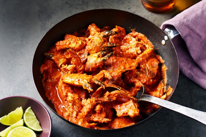 A black wok filled with cooked crab in a red chilli sauce