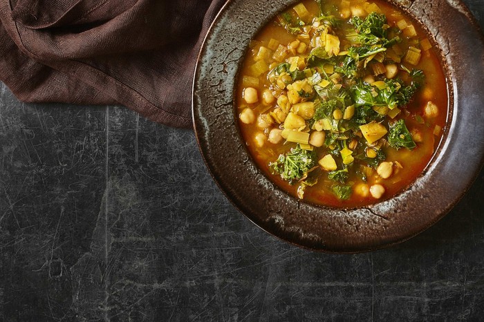 Green Lentil Soup Recipe With Harissa Two black bowls filled with green lentils and chickpeas in a broth