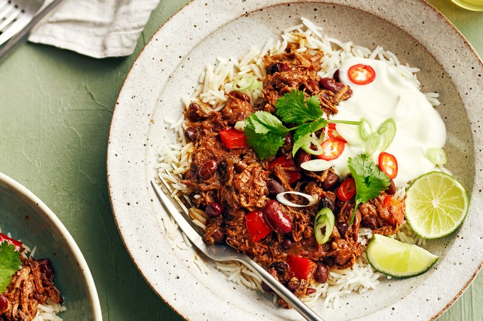 A plate of beef brisket with rice and lime wedges