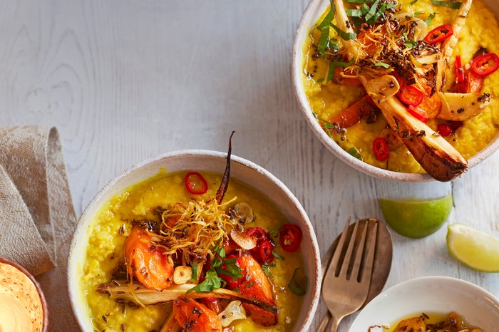 Two bowls filled with yellow dhal and topped with roast parsnips