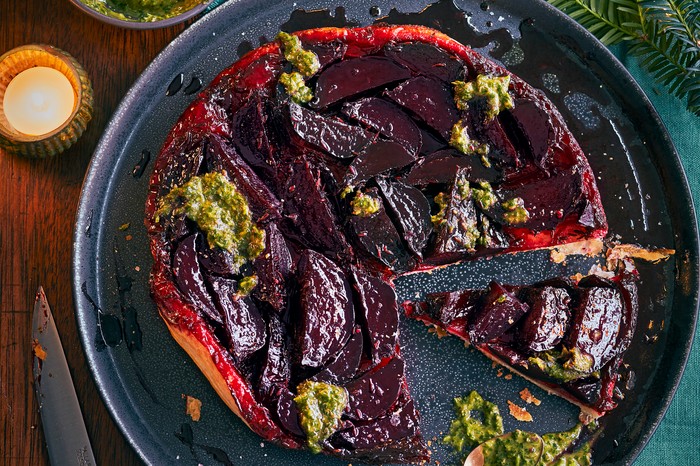 A round puff pastry tart topped with purple beetroots and green pesto