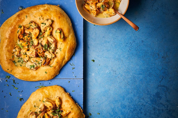 Two flatbreads on a blue serving platter with butter on the side