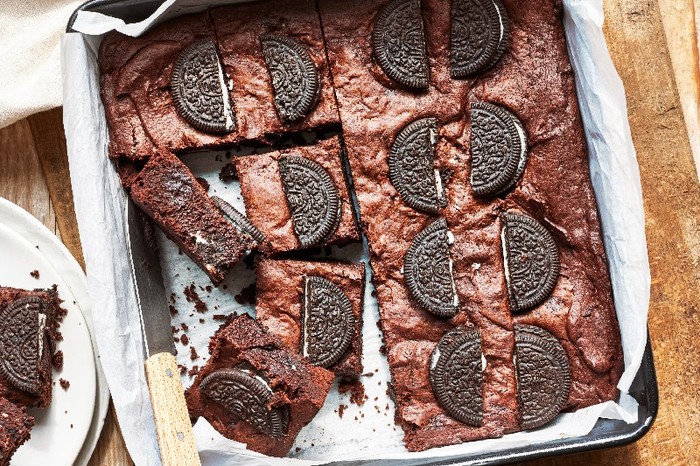 A baking tray lined with paper and filled with brownies topped with oreos