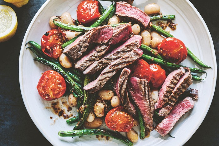 A salad of sliced steak, green beans and tomato