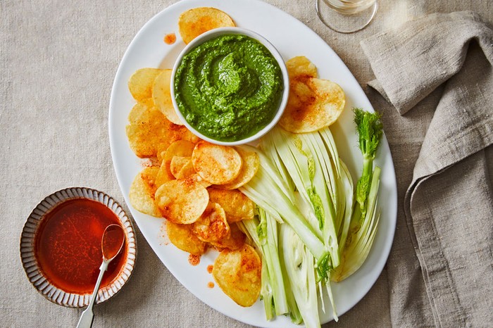 Crisps coated in paprika on a platter with fennel and a ramekin of mojo verde