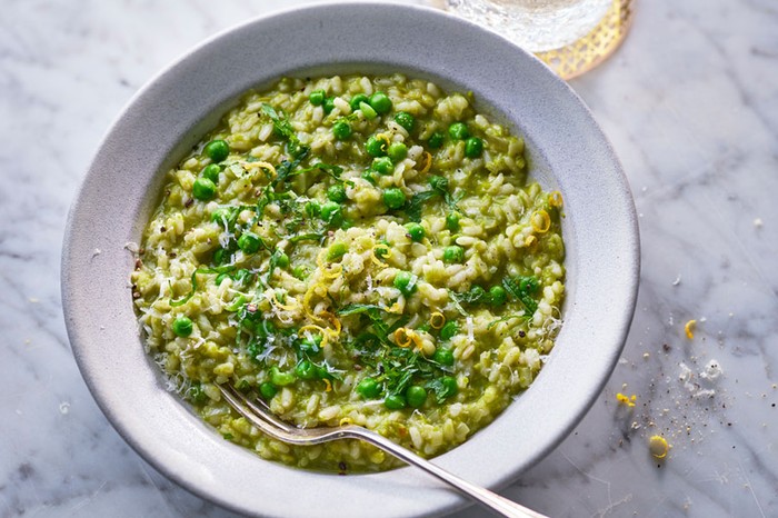 Bowl of pea risotto next to a glass of water