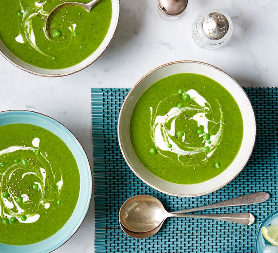 Three bowls of green spinach and pea soup, with a swirl of creme fraîche