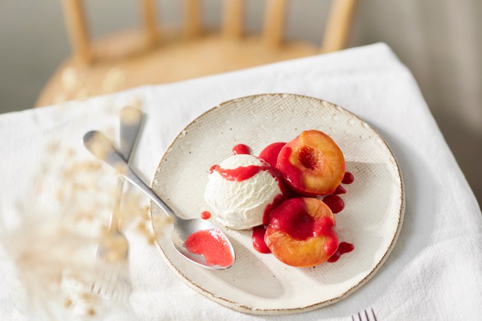 A plate of peach melba on a table set with a white tablecloth