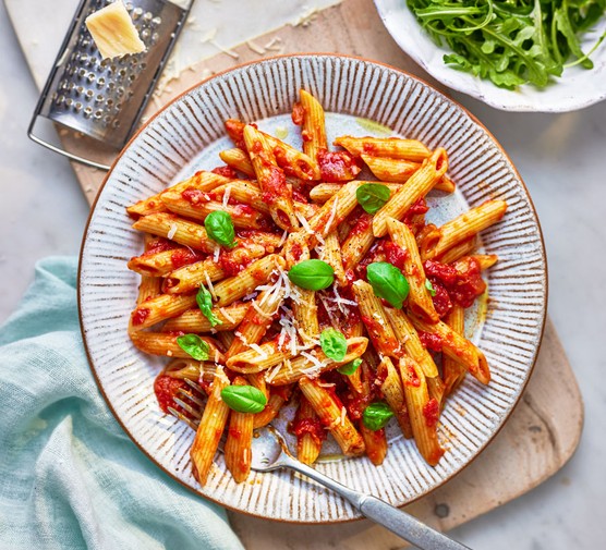 Penne pasta in tomato sauce topped with parmesan and basil