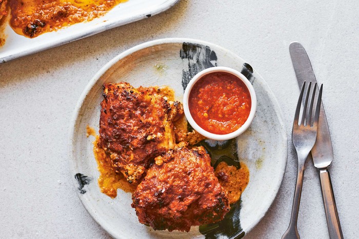 A plate of chicken with dip on the side