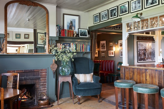 The Pheasant Inn Hungerford Pub area with a mirror above a fireplace and blue teal stools at a wooden bar