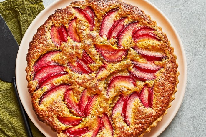 a plum tart on a peach plate with an olive green napkin