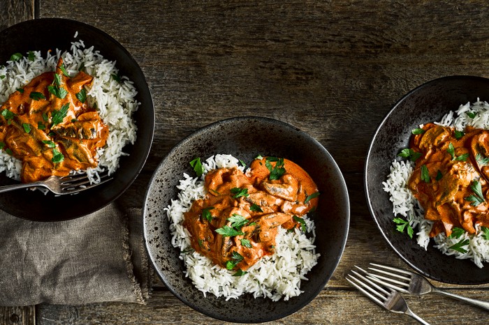 Vegetarian mushroom stroganoff with rice in three black bowls