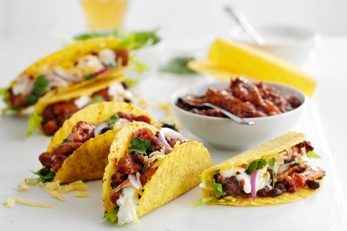 Pork and bean tacos A slate of tacos filled with pork, beans, red onion, soured cream and coriander