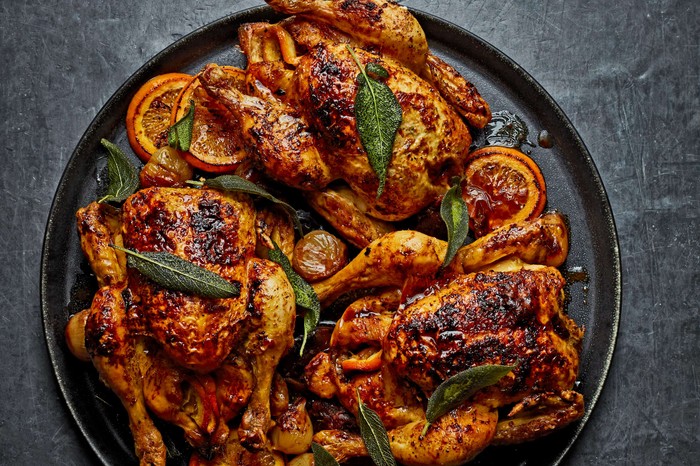 A platter of cooked poussins topped with sage