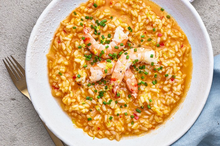 A bowl of prawn risotto topped with three large prawns