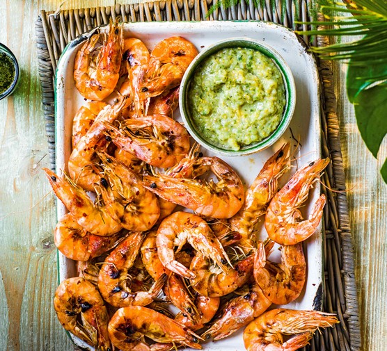 BBQ Prawns Recipe With Gooseberry Salsa A silver tray topped with juicy pink prawns with a green sauce on the side