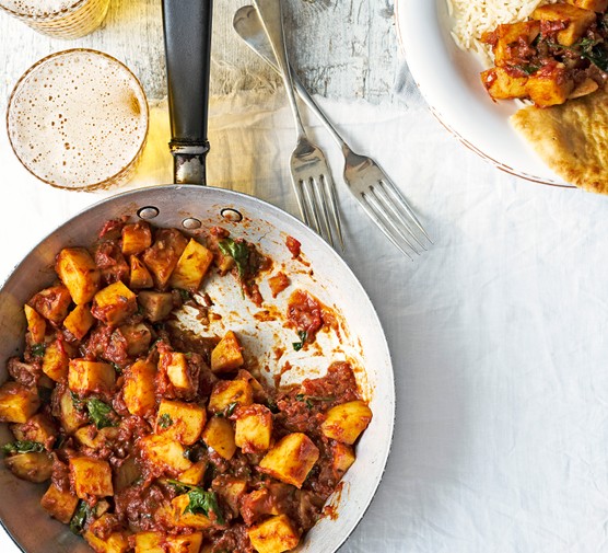 Potato Curry Recipe with tomatoes, coriander, chilli and ginger. With sides of rice, naan bread and cold beer