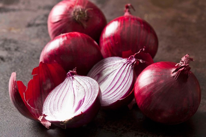 Whole and sliced red onions Rote Zwiebeln (Allium cepa), ganze, Hälften, dunkler Untergrund