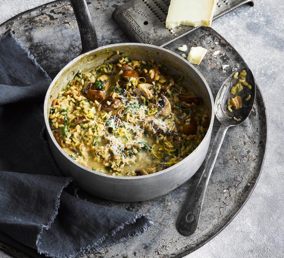 Mushroom risotto with lemon in a large silver pot with serving spoon