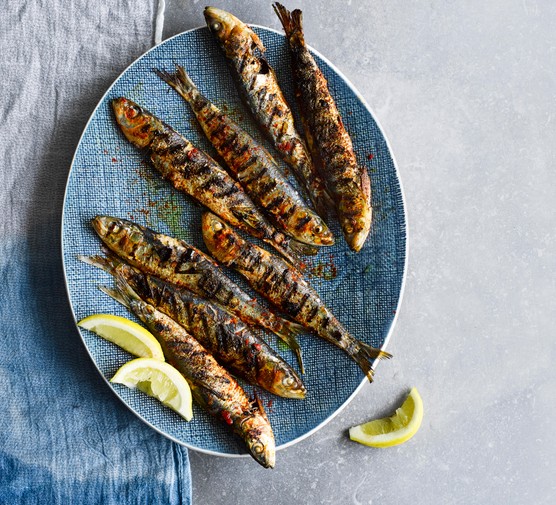 Grilled Portuguese Sardines served on an oval blue plate