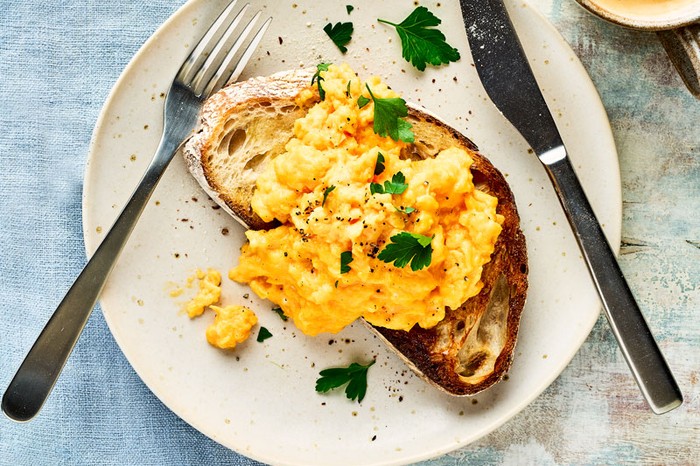 Scrambled eggs on toast, topped with parsley leaves