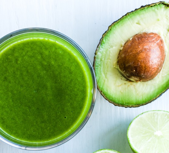 Healthy green smoothies Avocado and limes alongside a glass of green smoothie