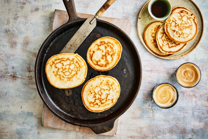 Three sourdough pancakes in a pan with a stack by the side