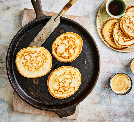 Sourdough Pancakes Recipe Three sourdough pancakes in a pan with a stack by the side