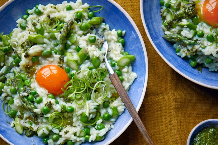 Two plates of spring risotto topped with an egg yolk