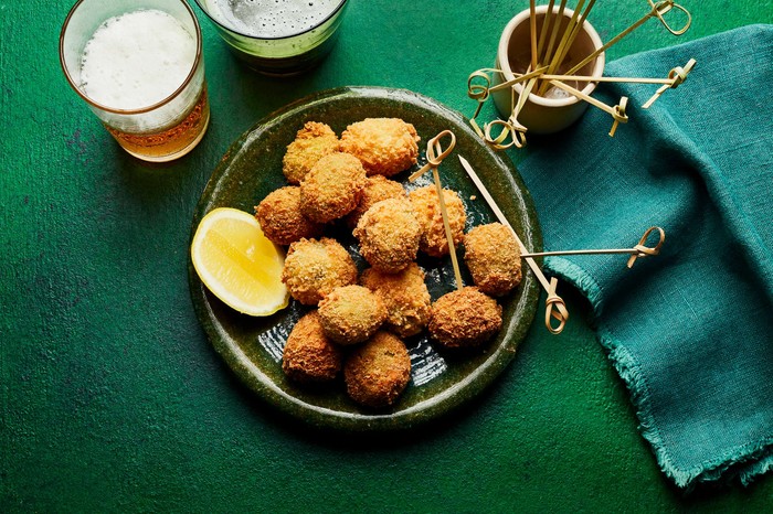 A small bowl of deep-fried olives with a wedge of lemon on the side