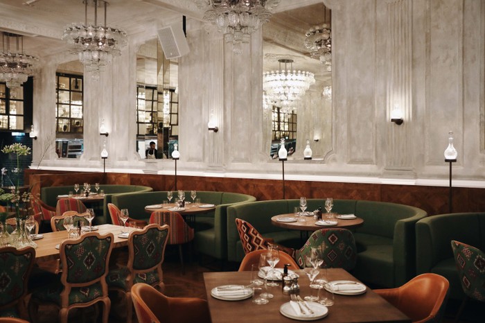 The high end interiors at Sucre, featuring chandeliers, dark green seating and large mirrors on the wall