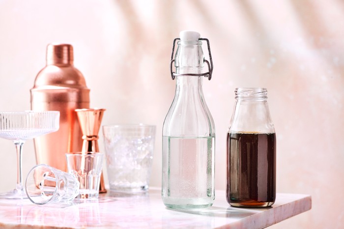 Bottles of sugar syrup next to a cocktail strainer