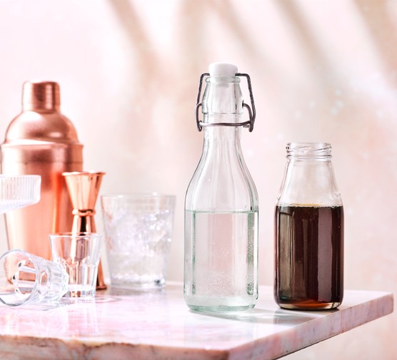 Bottles of sugar syrup next to a cocktail strainer