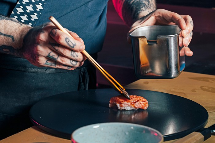 Sushi on Jones A pair of hands assembling a sushi dish at Sushi on Jones