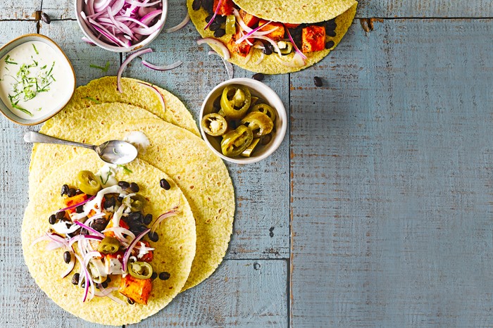 Tacos containing roasted squash, black beans, red onion and jalapeño slices