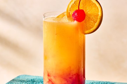 Tequila sunrise in glass with orange and cherry