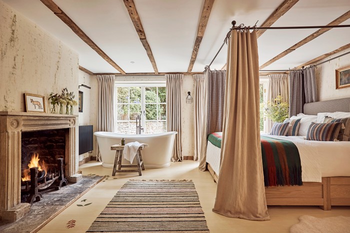 A wood-beamed room decorated with sheepskins, woollen rugs and quilted blankets