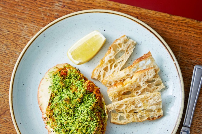 A blue serving plate with crab and bread sticks on the side